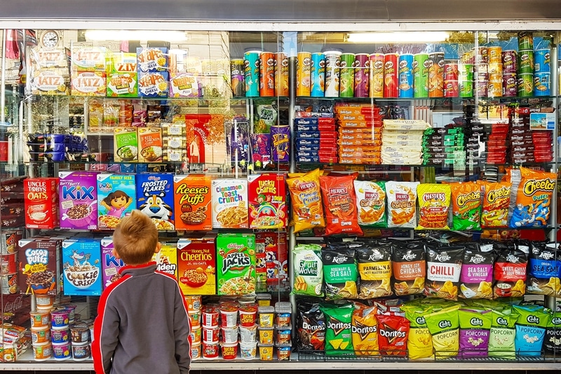 Young boy stands in front of grocery shelves